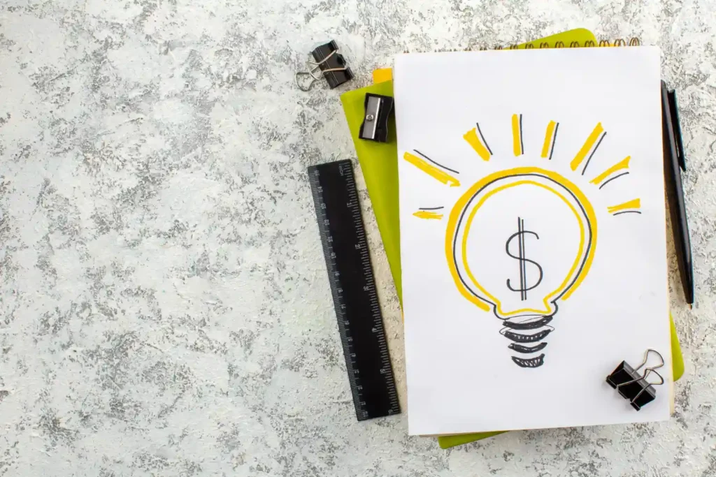 Imagem de uma lâmpada com símbolo de dólar, representando a validação de ideias para investimentos, com materiais de escritório ao redor, ideal para aprender como validar uma ideia antes de investir dinheiro.