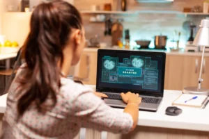Como Proteger Computadores e Dados Contra Os Principais Golpes Digitais: mulher usando um notebook com tela de segurança e acesso autorizado em um ambiente doméstico, com mesa de trabalho e itens ao lado.